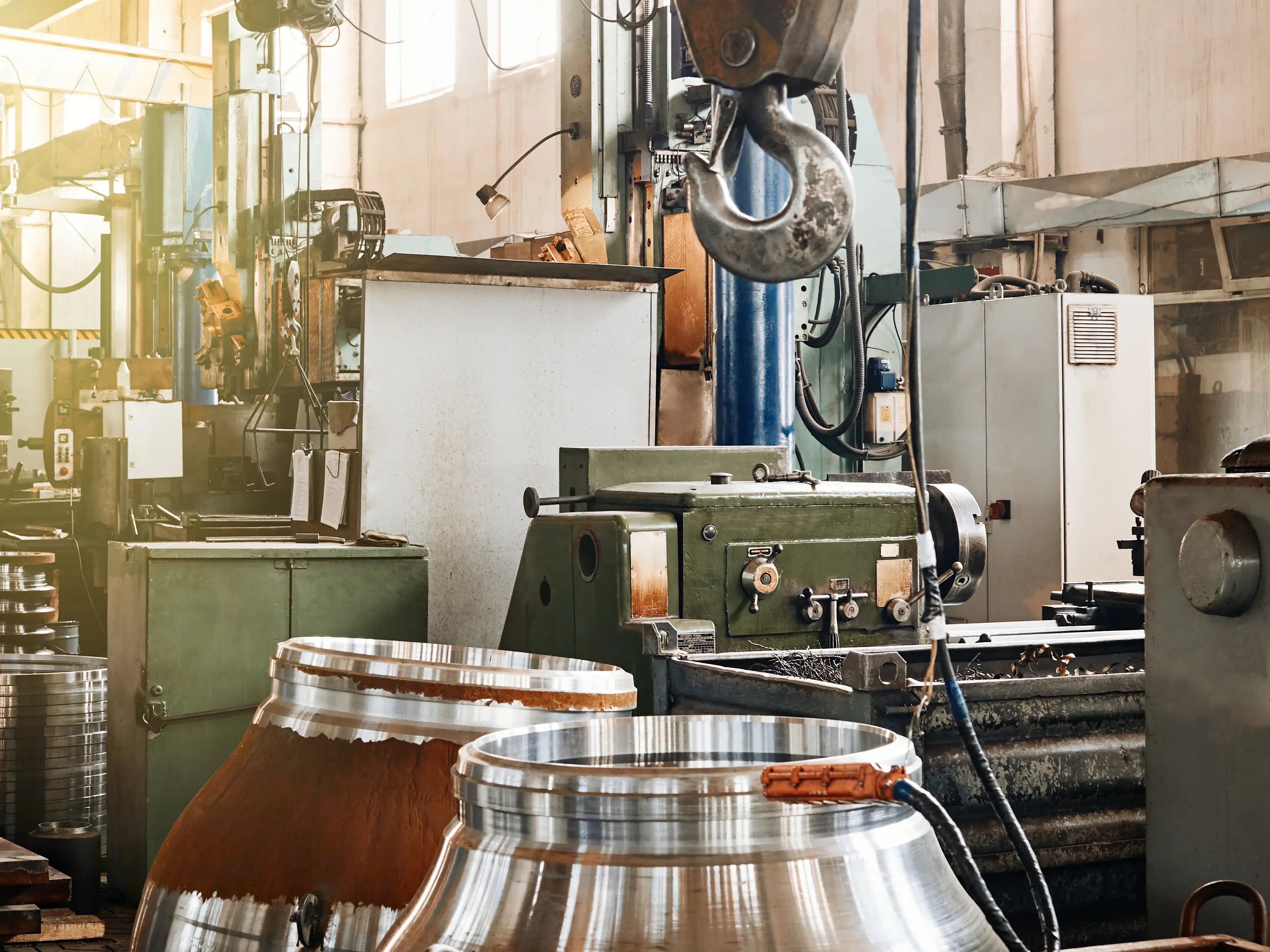 Máquinas industriais de usinagem em chão de fábrica, com peças metálicas em produção, ilustrando diferentes níveis de criticidade de equipamentos industriais conforme impacto na produção e no fluxo operacional.