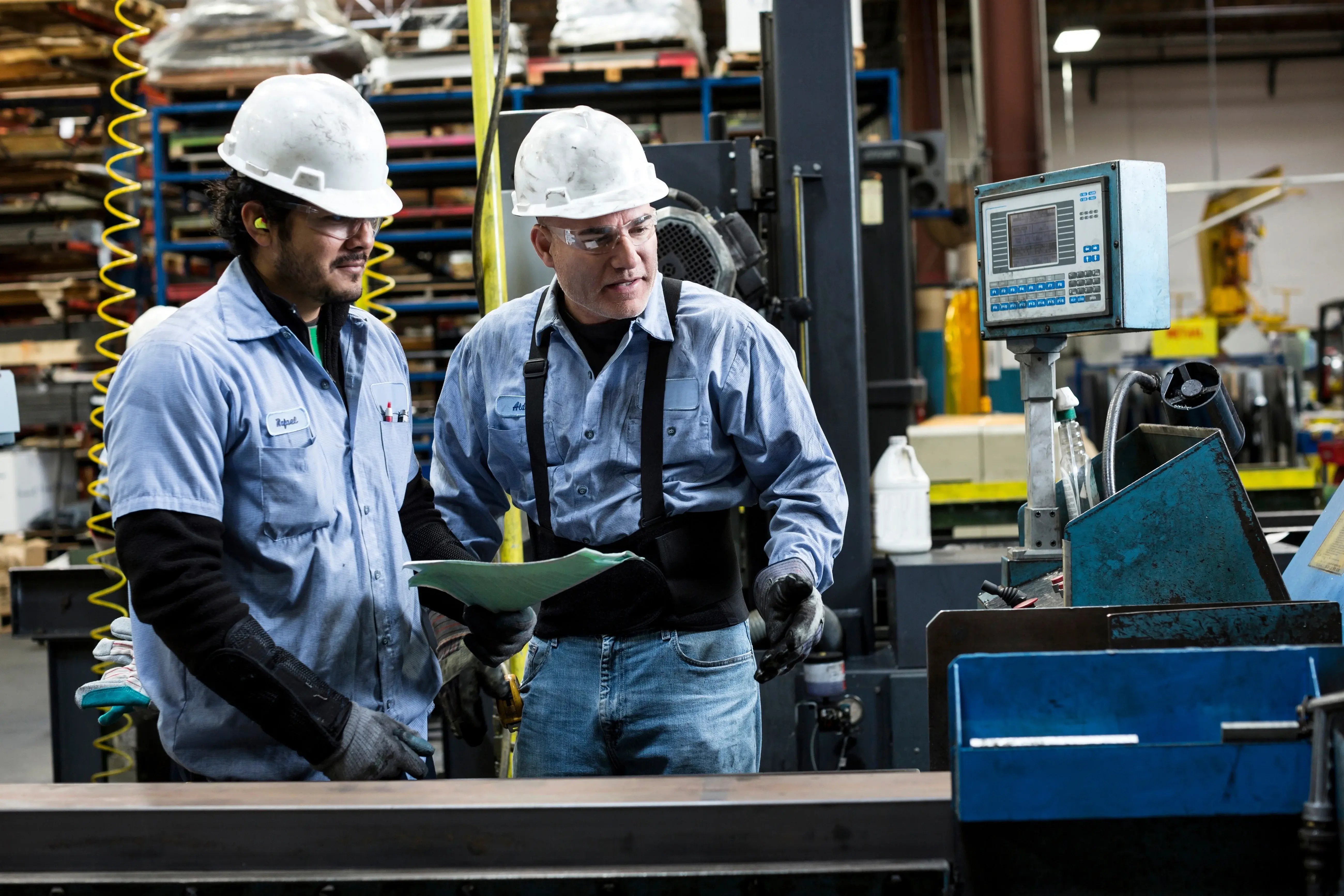 Técnicos industriais analisando máquina em fábrica, exemplo de aplicação do Lean Manufacturing com foco em eficiência operacional e redução de desperdícios.