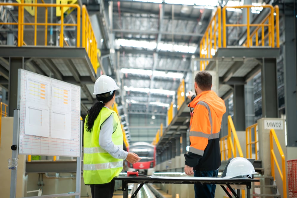 Técnicos de manutenção industrial avaliando equipamentos e planejamento de manutenção preventiva em fábrica