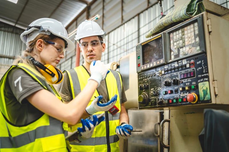 Equipe de manutenção analisando painel de máquina industrial durante intervenção técnica para melhorar o tempo de ciclo e a eficiência operacional