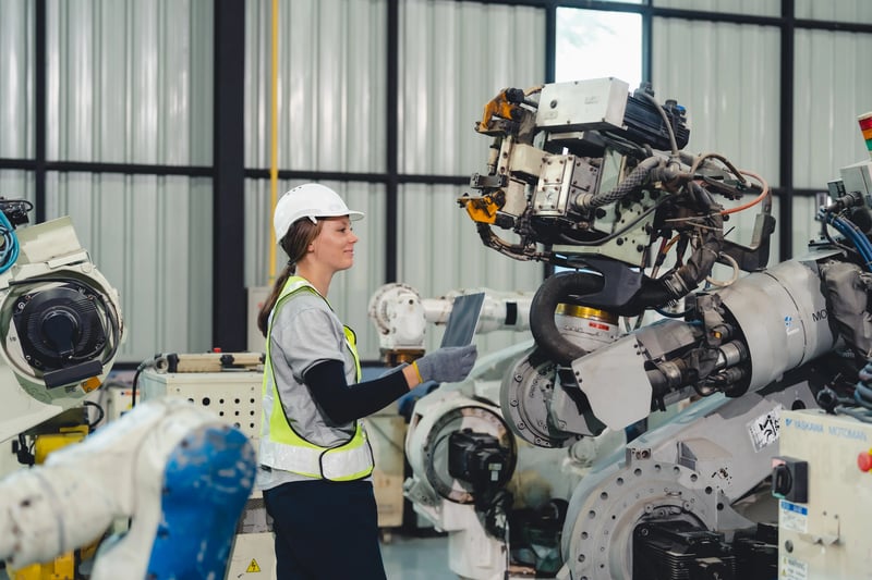 Engenheira operando braços robóticos em ambiente industrial inteligente com automação e agentes de IA para decisões operacionais.