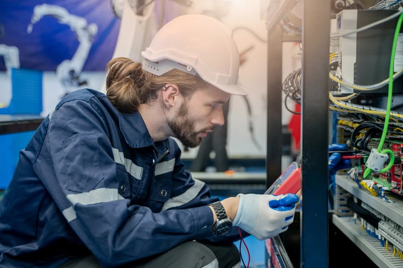 Técnico avalia equipamento automatizado com apoio de ferramentas lean na manutenção industrial.