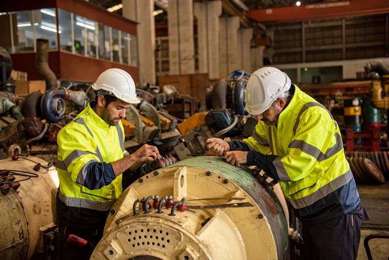 Engenheiros inspecionam motor elétrico de grande porte em fábrica