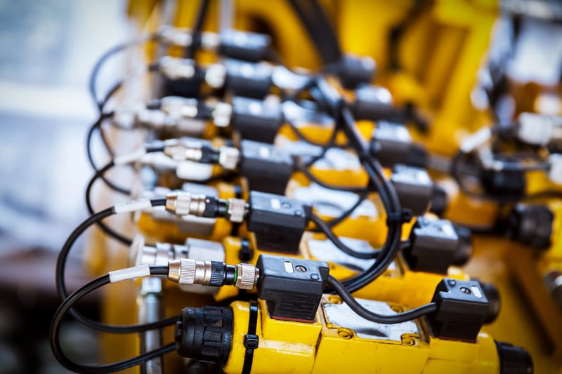 Sensor de vibração industrial conectado por cabos elétricos a dispositivo de monitoramento em ambiente de automação industrial.