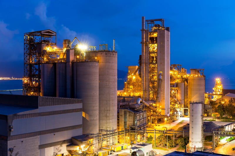 Vista noturna de planta de cimento com silos e equipamentos, exemplo de aplicação de solução de monitoramento de ativos industriais.