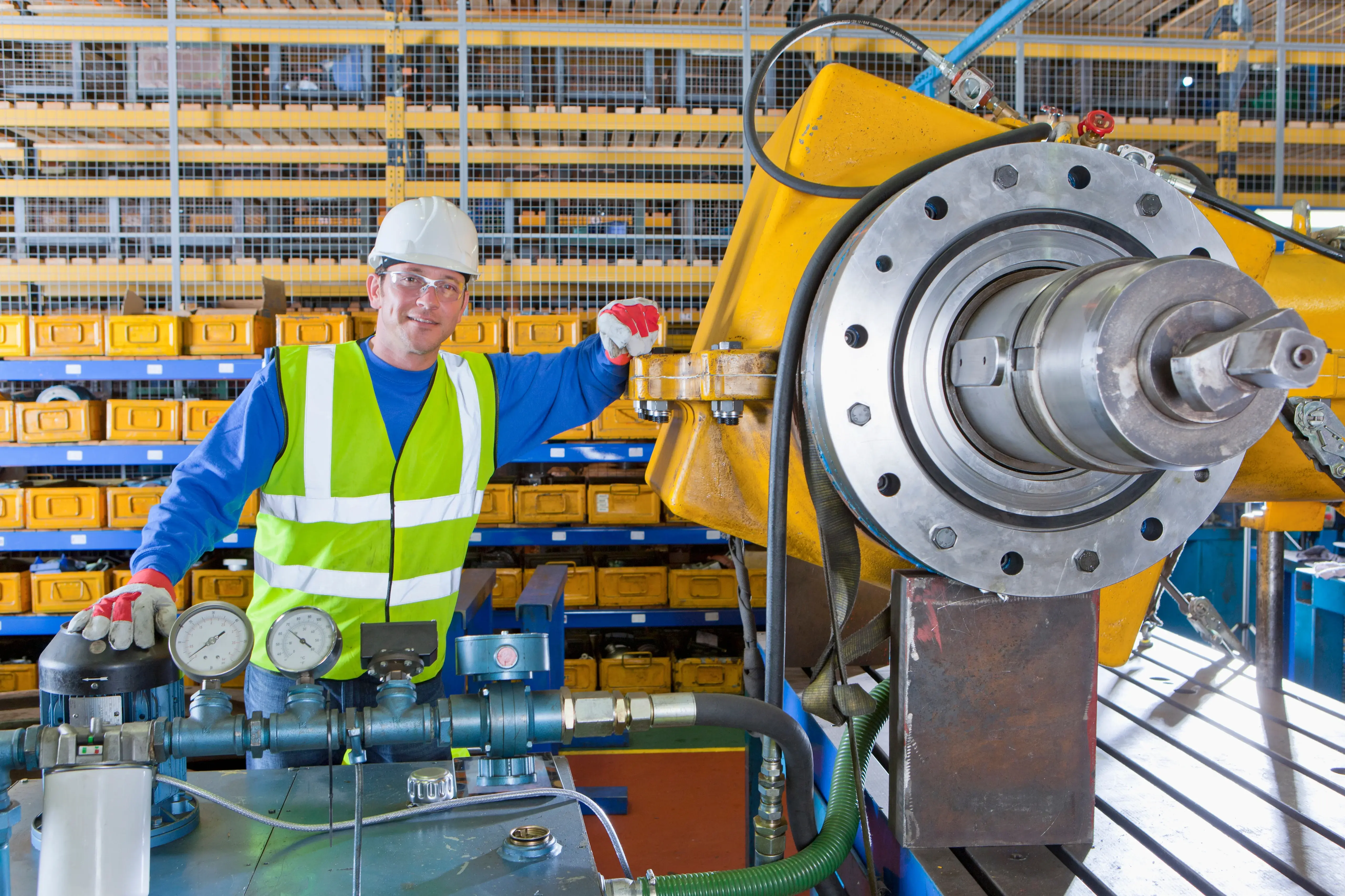 Técnico de manutenção industrial inspecionando equipamento hidráulico de grande porte em ambiente fabril, exemplo de ativo de alta criticidade de equipamentos industriais devido ao impacto na operação e na segurança.