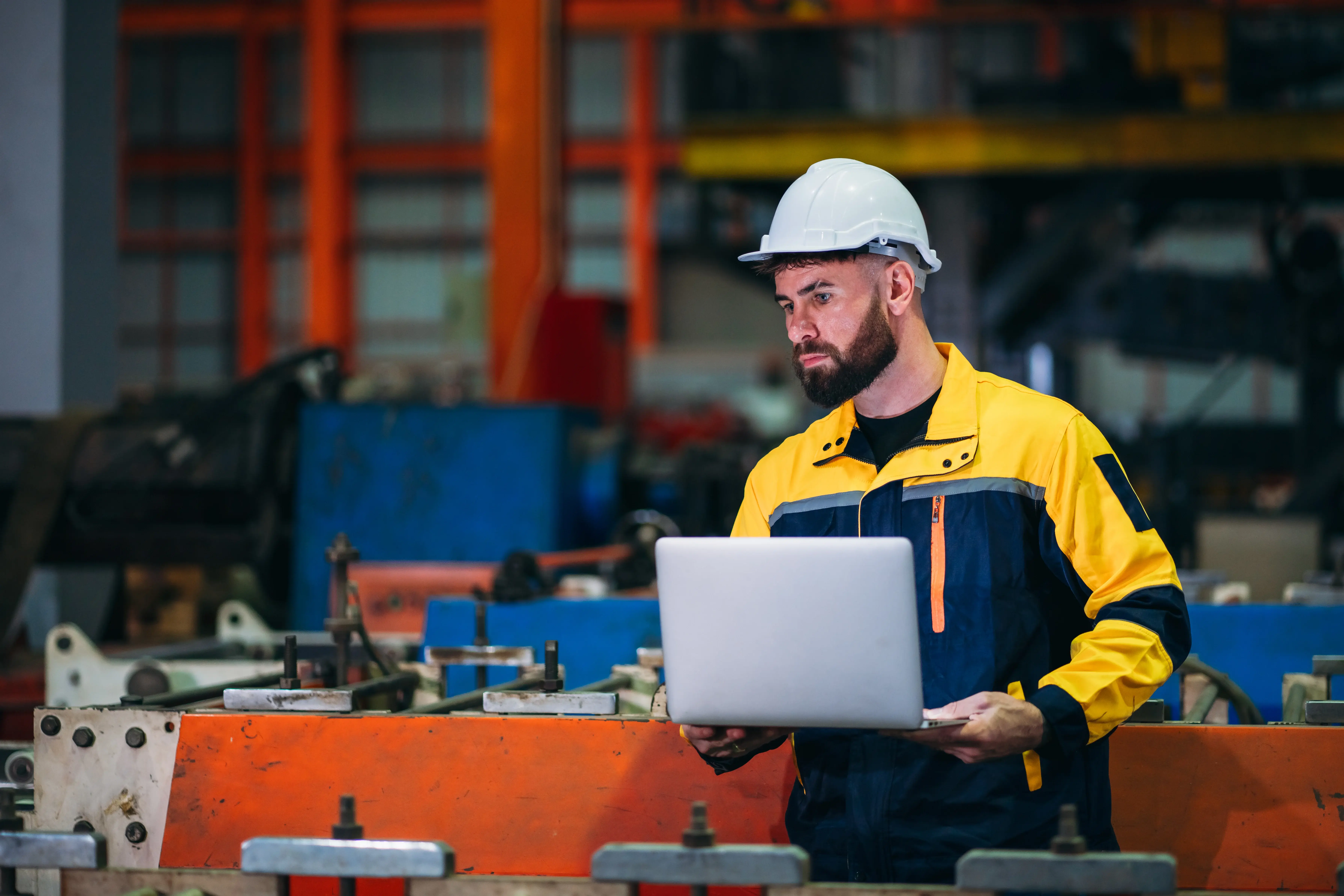 Técnico de manutenção em ambiente industrial utilizando notebook para registrar ordens de serviço em um sistema CMMS durante a operação dos equipamentos.