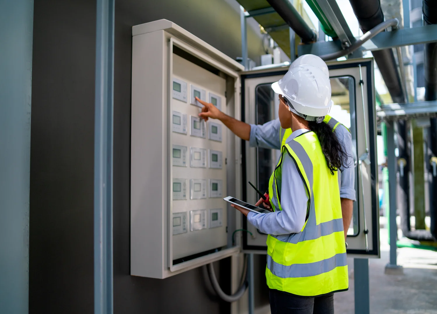 dois profissionais de manutenção realizando manutenção corretiva em um painel elétrico