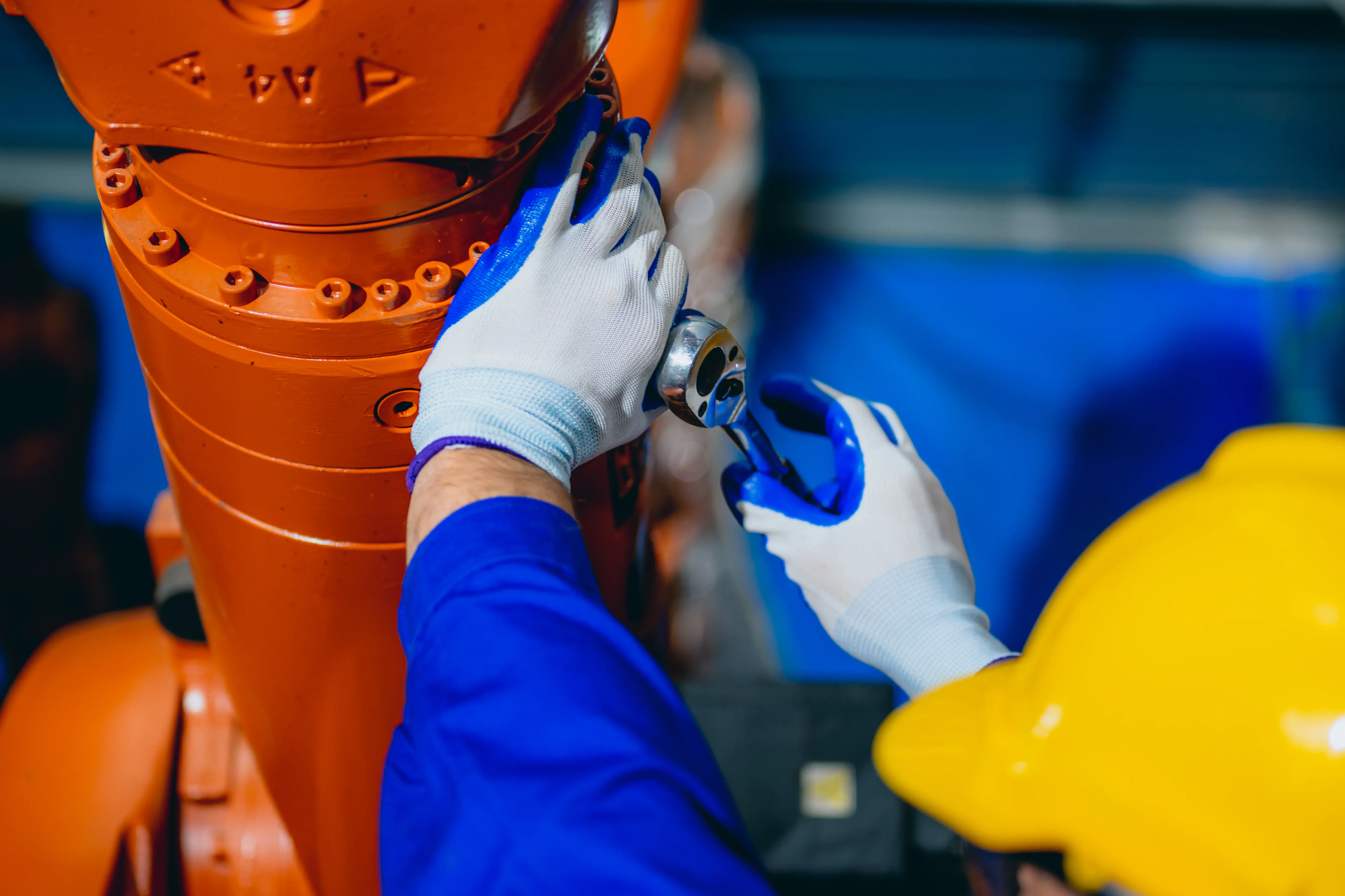 Profissional inspeciona máquina robotizada com sensor de manutenção preditiva em ambiente industrial.